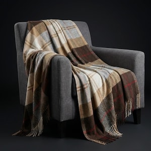 Può includere: Una coperta a quadri drappeggiata su una poltrona grigia. La coperta presenta un motivo di quadrati marroni, beige, grigi e bianchi con accenti rossi. La coperta ha un bordo con frange ed è realizzata in un materiale morbido.