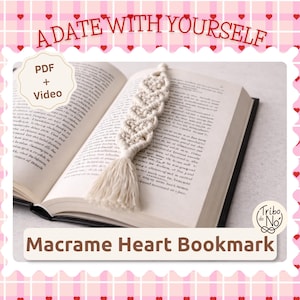 Pode incluir: Um marcador de página de macramé cor de creme em forma de coração com uma borla, sobre um livro aberto. A imagem inclui o texto A DATE WITH YOURSELF, PDF + Video e Macrame Heart Bookmark, com um logótipo com o texto Tribo do No.