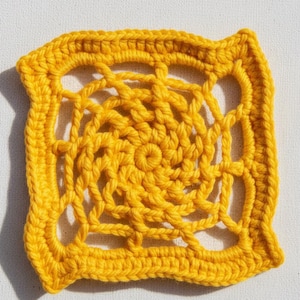 May include: A square, handmade crochet doily in a vibrant yellow hue. The intricate design features a central spiral pattern surrounded by openwork and a solid border. The texture is clearly visible, showcasing the yarn's loops and knots.