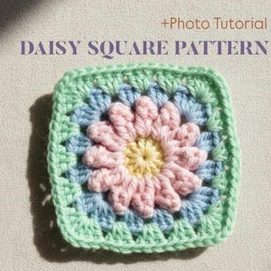 May include: A square crochet pattern featuring a daisy design. The center of the daisy is yellow, surrounded by pink petals, blue, and a green border. The text "DAISY SQUARE PATTERN" is at the top.