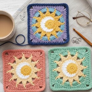 May include: Three crocheted square coasters with sun and moon designs. The coasters are in shades of blue, peach, and green, with yellow and white accents. A cup of coffee, glasses, and a crochet hook are also in the image.