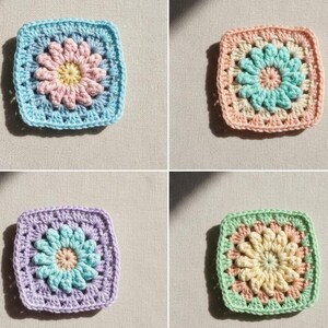 May include: Four colorful, square crochet pieces with a daisy design. Each piece features a different color scheme: blue with pink and yellow, peach with teal and pink, purple with teal and beige, and green with yellow and peach.