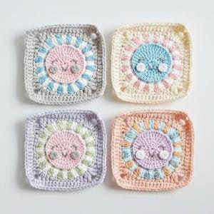 May include: Four handmade crochet squares in pastel colors. Each square features a central sun-like design with a smiling face. The squares are in shades of gray, cream, lavender, and peach, with blue, pink, and green accents.