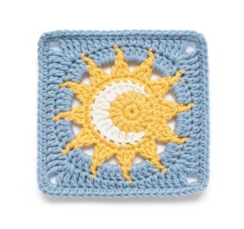 Pode incluir: Uma pe&ccedil;a quadrada de croch&ecirc; com um desenho de sol e lua. O sol &eacute; amarelo com uma lua crescente branca no centro, sobre um fundo azul claro. As bordas tamb&eacute;m s&atilde;o azul claro.