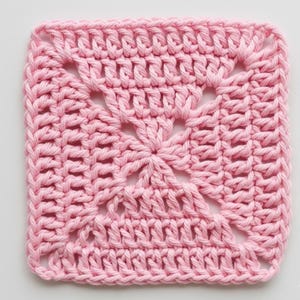 May include: A square, handmade crochet piece in a soft pink hue. The design features an openwork pattern in the center, surrounded by a dense, textured border. The square is approximately 6 inches by 6 inches, perfect for various craft projects.