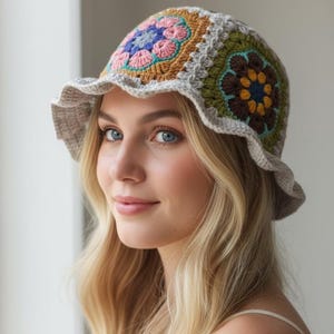 May include: A crocheted bucket hat with a colourful floral design. The hat features a scalloped brim and is made with various colours including pink, blue, green, and brown. The hat is a stylish accessory.