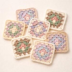 May include: Seven pastel-colored, square crochet coasters. Each coaster features a central floral design in shades of pink, green, and cream, surrounded by concentric rings of color. The edges are finished with a cream-colored border.