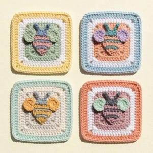 May include: Four handmade crochet coasters, each featuring a square design with a bee motif. The bees have striped bodies and wings, set against pastel backgrounds of yellow, blue, green, and orange. The coasters are square, approximately 4 inches by 4 inches.
