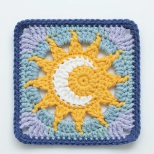 Pode incluir: Quadrado de croch&ecirc; com um desenho de sol e lua. O sol &eacute; amarelo com uma lua crescente branca. O quadrado tem uma borda azul e detalhes em azul claro e lavanda. Mede aproximadamente 20 cm x 20 cm.