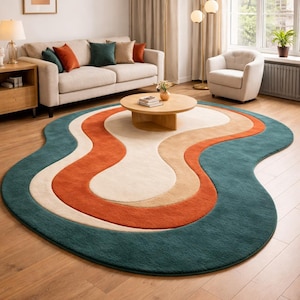 May include: A colorful, abstract area rug with a wavy design. The rug features a teal border, with interior sections of orange, beige, and cream. The rug is placed on a hardwood floor in a living room setting.