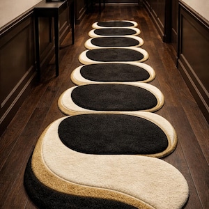 May include: A series of oval-shaped hallway rugs in a modern design. Each rug features a black center, bordered by a cream and gold accent. The rugs are arranged in a line down a dark wood hallway.