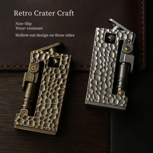 Op de afbeelding: Twee metalen aanstekers met een textuur, kraterachtig ontwerp. E&eacute;n aansteker is bronskleurig, de andere zilver. De aanstekers hebben scharnierende deksels en zijn gemarkeerd met "Retro Crater Craft", "Non-Slip", "Wear-resistant" en "Hollow-out design on three sides".