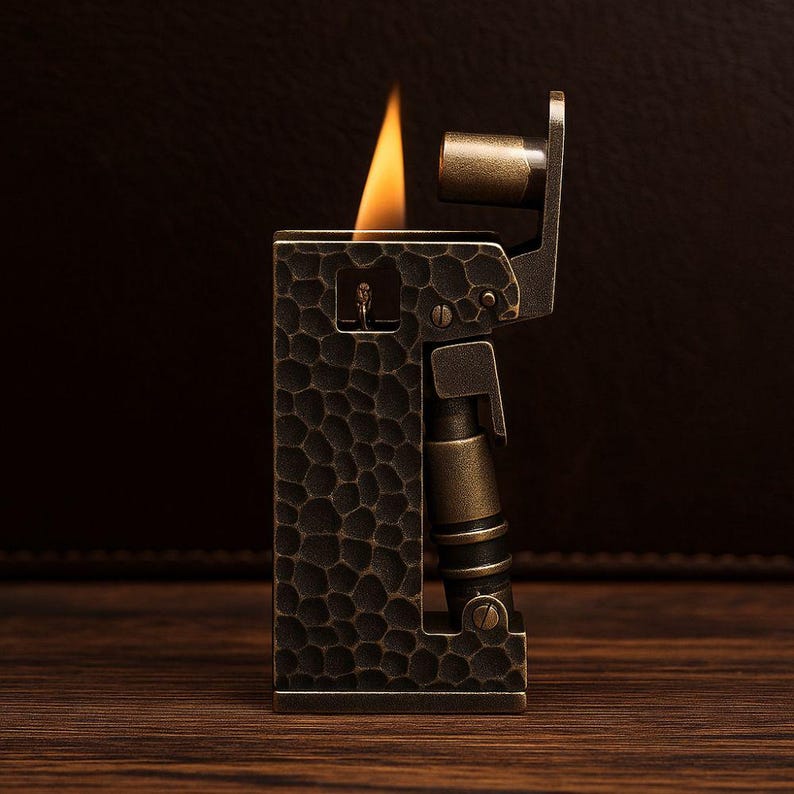 Op de afbeelding: Een vintage-stijl aansteker met een getextureerde, donkerbronzen afwerking. De aansteker heeft een rechthoekige behuizing met een gedetailleerd patroon en een vlam die van bovenaf komt. Het ontwerp bevat metalen accenten en een mechanische uitstraling.