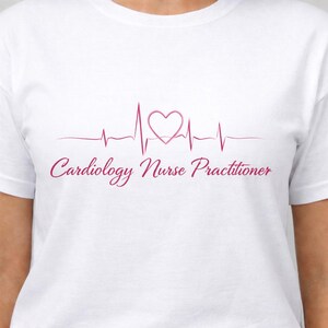Puede incluir: Camiseta blanca con un dise&ntilde;o de electrocardiograma rosa con un s&iacute;mbolo de coraz&oacute;n. El texto "Cardiology Nurse Practitioner" est&aacute; impreso debajo en una fuente cursiva. La camiseta est&aacute; hecha de un material suave y c&oacute;modo.
