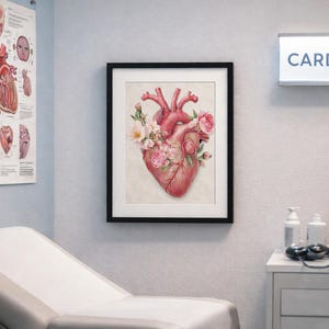 Puede incluir: Impresi&oacute;n enmarcada de acuarela de un coraz&oacute;n humano adornado con flores rosas y blancas. La obra de arte se exhibe en un entorno m&eacute;dico, con un letrero de cardiolog&iacute;a en el fondo. La impresi&oacute;n est&aacute; en un marco negro.