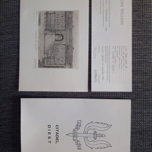 May include: A collection of white paper ephemera, including a detailed pencil drawing of a stone building with a gate, a card with text, and a card with the words "CITADEL DIEST" and a sword and wing emblem.