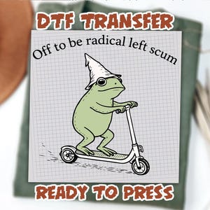 May include: A DTF (Direct to Film) transfer featuring a cartoon frog riding a scooter, wearing a hat, and the text "Off to be radical left scum." The words "READY TO PRESS" are also displayed.