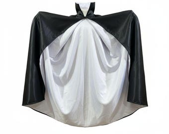 May include: A black and white cape with a high collar. The cape is black on the outside and white on the inside. The collar is white with a black bow tie. The cape is made of a shiny material.