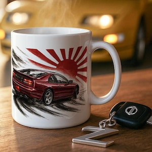 Può includere: Tazza in ceramica bianca con un design di auto sportiva rossa e un sole nascente. Una chiave Nissan e un'auto sportiva gialla sono sullo sfondo. Il vapore sale dalla tazza.