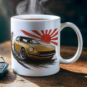 May include: White ceramic coffee mug featuring a yellow vintage car design with a red sunburst and a rising sun. The mug is filled with coffee, and steam rises from the top. Car keys are next to the mug.