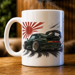 May include: A white ceramic mug featuring a graphic illustration of a dark green sports car with a large rear spoiler. The design includes a red sunburst pattern behind the vehicle and black tire skid marks underneath, with steam rising from the top.