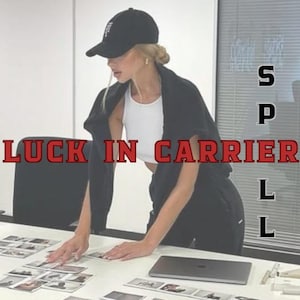 Op de afbeelding: Een persoon met een zwarte baseballpet, witte top en zwarte jas staat boven een tafel met foto's en een laptop. De tekst "LUCK IN CARRIER" wordt in rode letters weergegeven.