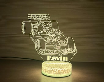 May include: A glowing LED night light featuring a Formula 1 race car design. The light is white and has the name "Kevin" at the base. The base of the light is a round, textured design.
