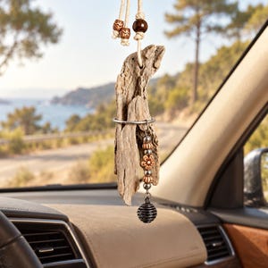 Peut inclure: Un ornement suspendu pour rétroviseur de voiture composé d'un morceau de bois flotté brun clair suspendu par une cordelette crème. Le bois flotté est agrémenté de petites perles en bois, d'un anneau métallique et d'une breloque à perles.