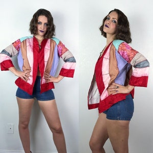 May include: A patchwork jacket in a variety of colors, including red, pink, tan, and lavender. The jacket has a V-neck and three-quarter sleeves. The jacket is open in the front and has a unique, vintage style.