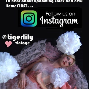 May include: A woman in a pink and white dress is surrounded by white paper flowers. The image includes the text "Follow us on Instagram" and the shop's Instagram handle, "@tigerlilyvintage."