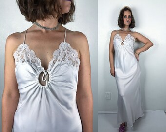 Könnte beinhalten: Weißes Satin-Schlafkleid mit Spitzenbesatz und einem Schlüssellochausschnitt am Dekolleté.