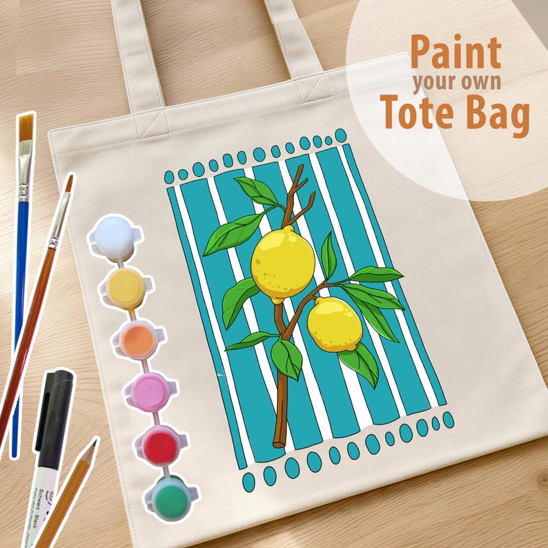 May include: A cream-colored canvas tote bag featuring a printed design of two yellow lemons on a brown branch against a background of vertical teal and white stripes. The text Paint your own Tote Bag is printed in brown. Includes paint pots and brushes.