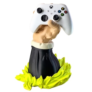 Könnte beinhalten: Ein weißer kabelloser Xbox-Controller, gehalten von einer skulptierten Hand, die aus einem schwarzen Ärmel mit weißer Manschette ragt. Die Basis ist von hellgelben, flammenartigen skulptierten Details umgeben. Der Controller hat schwarze Joysticks.