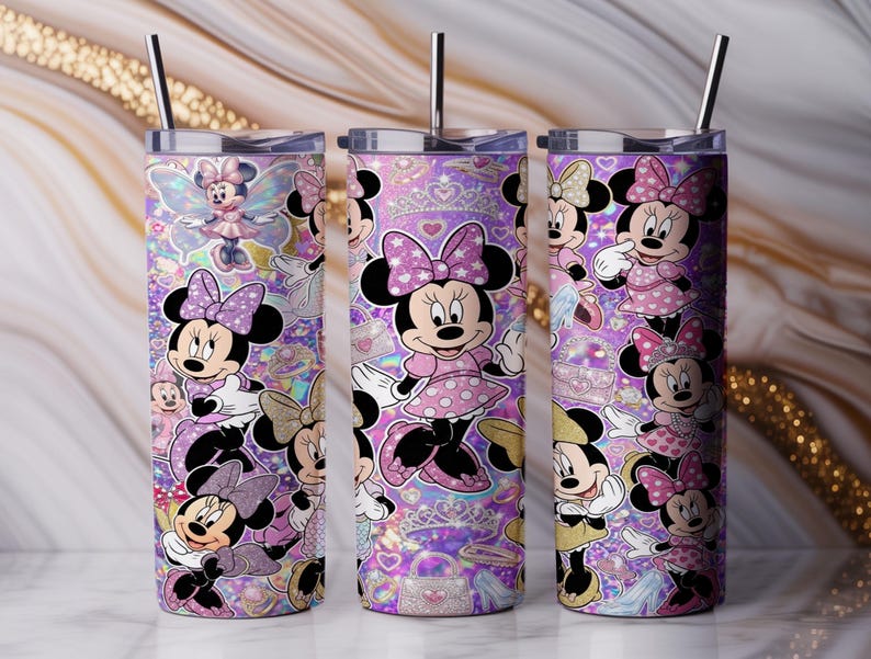 Op de afbeelding: Drie cilindervormige roestvrijstalen bekers met deksels en metalen rietjes, voorzien van een herhalend patroon van Minnie Mouse in diverse houdingen, gekleed in roze jurken met stippen en strikken op een paarse glitterachtergrond.
