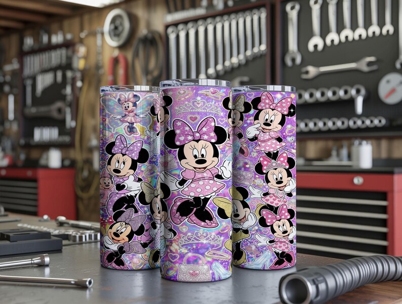 Op de afbeelding: Drie cilindrische bekers met een herhalend patroon van Minnie Mouse in verschillende houdingen, gekleed in roze jurken met stippen en strikken. De achtergrond is een levendig paars met glinsterende ster-, hart- en tiaramotieven.