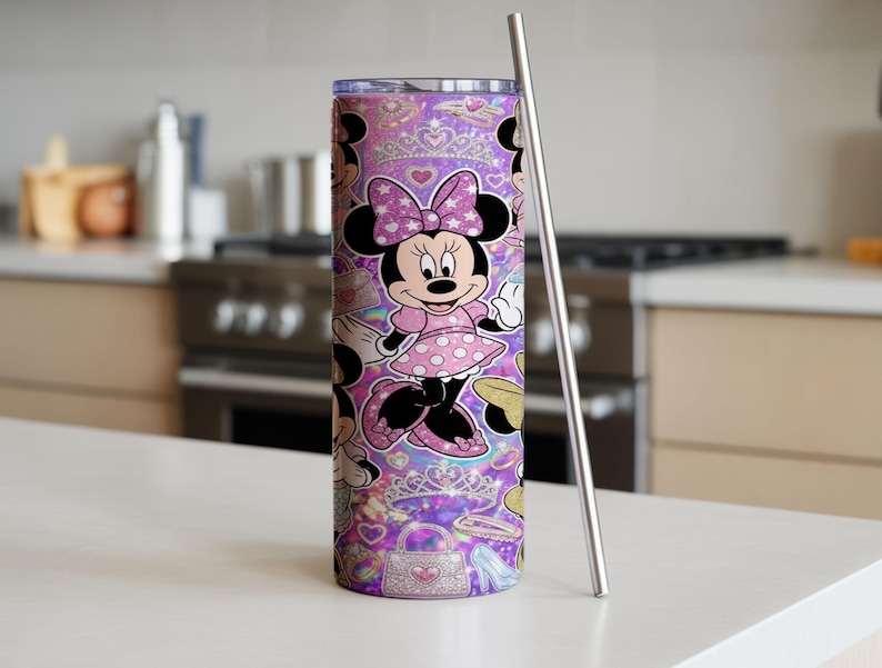 Op de afbeelding: Een cilindervormige roestvrijstalen beker met een herhalend patroon van Minnie Mouse in een roze jurk met stippen en strik, afgewisseld met glinsterende tiara's, handtassen en hartjes op een levendige paarse achtergrond, inclusief een metalen rietje.