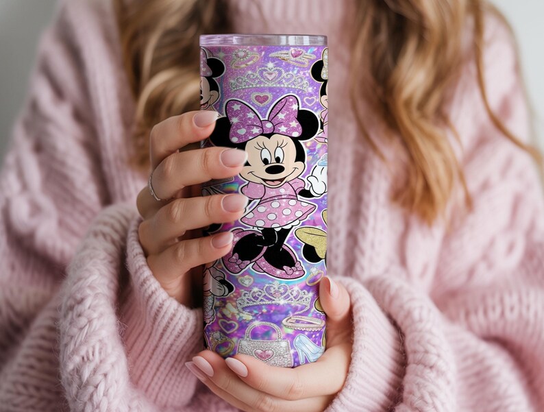 Op de afbeelding: Een cilindrische roestvrijstalen beker met een paarse glitterachtergrond en een herhalend patroon van Minnie Mouse, sprankelende tiara's, handtassen en hartvormen. Het ontwerp bevat een doorzichtig deksel en een gladde afwerking.