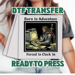May include: A white DTF transfer with the text "DTF TRANSFER" and "READY TO PRESS". The image on the transfer shows a medieval knight at a computer with the text "Born to Adventure" and "Forced to Clock In".