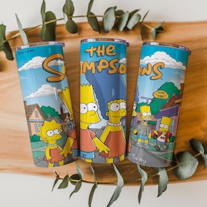 Op de afbeelding: Drie roestvrijstalen bekers met de personages van The Simpsons. Elke beker heeft een blauwe achtergrond met wolken en het logo van de show. De personages Lisa, Marge, Bart en Homer zijn afgebeeld op de bekers.
