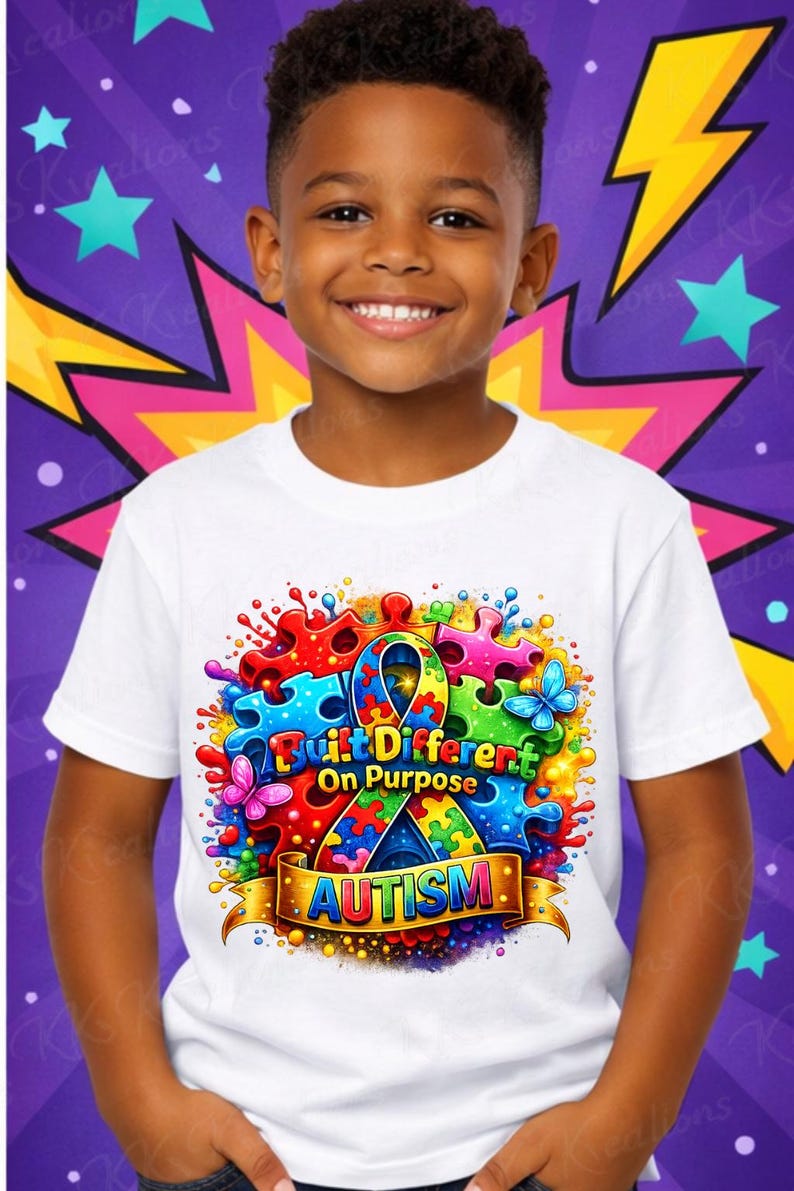 May include: A white t-shirt featuring a colorful graphic design with puzzle pieces, butterflies, and the text "Built Different On Purpose" and "Autism". The design is set against a purple background with star and lightning bolt accents.