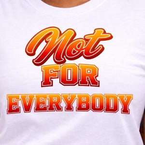 May include: White t-shirt with the text "Not FOR EVERYBODY" in a bold, orange and red gradient font. The text is centered on the chest of the shirt. The shirt has short sleeves.