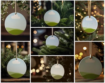 May include: Round ceramic ornaments with a landscape design. Each ornament features a light blue sky with a white cloud and green rolling hills. They hang from a beige ribbon, perfect for holiday decorating.