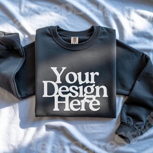 Pode incluir: Um moletom cinza escuro com o texto "Your Design Here" em branco. O moletom est&aacute; colocado sobre uma superf&iacute;cie branca. As mangas est&atilde;o dobradas. A imagem tamb&eacute;m inclui os logotipos Canva, Photoshop e Procreate.