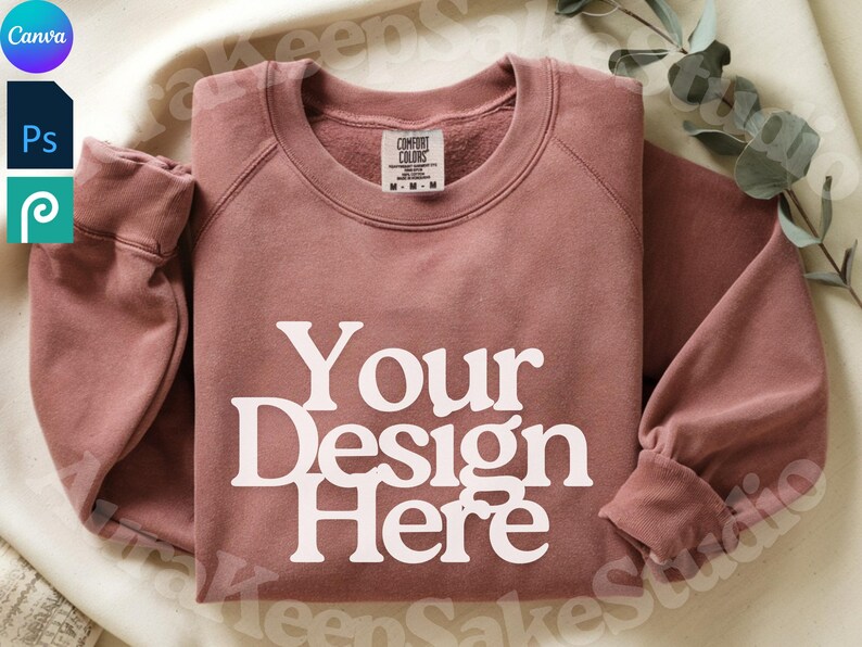 Pode incluir: Um moletom rosa empoeirado com o texto "Your Design Here" em letras brancas. O moletom tem gola redonda e mangas compridas. A etiqueta Comfort Colors &eacute; vis&iacute;vel.