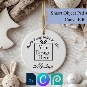 May include: A round white ceramic ornament hanging by a gold string. The centre features black text that reads Aura Keepsake studio, Your Design Here, and Mockup. A blue banner at the top displays Smart Object Psd + Jpg + Canva Edit.