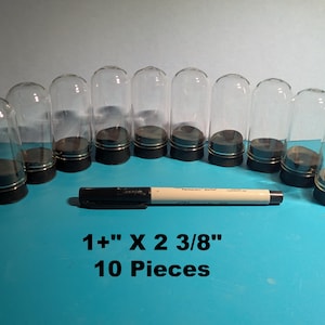 May include: Ten clear glass display domes with black bases. The domes are 1 inch in diameter and 2 3/8 inches tall.