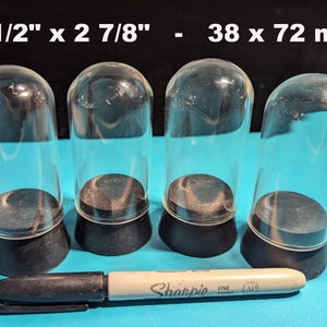 May include: Four clear glass dome display cases with black bases. The domes are 1 1/2" x 2 7/8" - 38 x 72 mm.