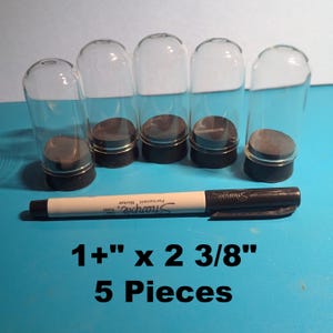 May include: Five clear glass vials with black bases and a Sharpie marker. The vials are approximately 1 inch by 2 3/8 inches. The text on the image reads "1+" x 2 3/8" 5 Pieces".