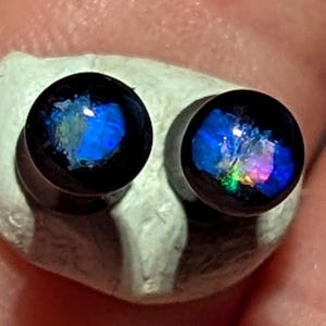 May include: Two black and blue opal earrings with iridescent rainbow colors.