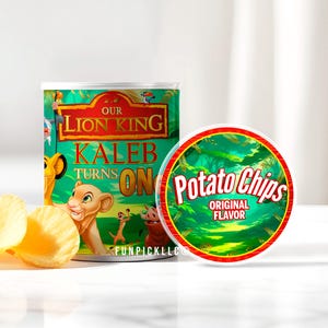 May include: A can of potato chips with a custom design featuring characters from Disney's The Lion King. The can is green with the words "Our Lion King" and "Kaleb Turns On". The lid reads "Potato Chips Original Flavor". Several potato chips are in front of the can.
